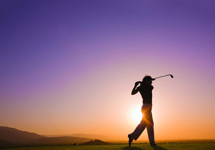 Female golfer follows through after driving ball